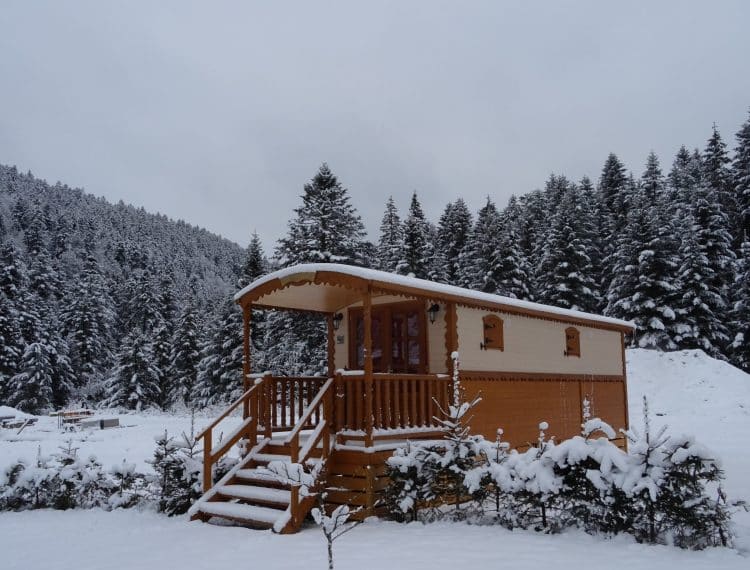Roulotte en hiver sous la neige dans le camping Belle Hutte à La Bresse